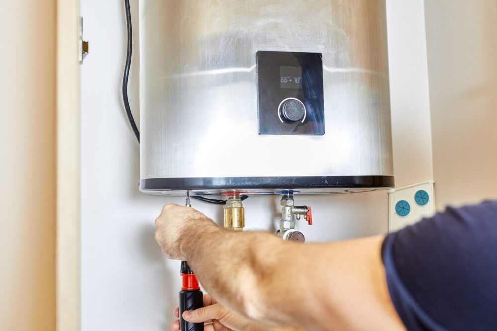 Man tightens the pipe nut in the water heating system. The master installs the water heater.